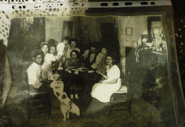 una foto vera di una famiglia con il capoi famiglia alc entro e al centro della tavola un unico piatto da cui tutti attingevano
